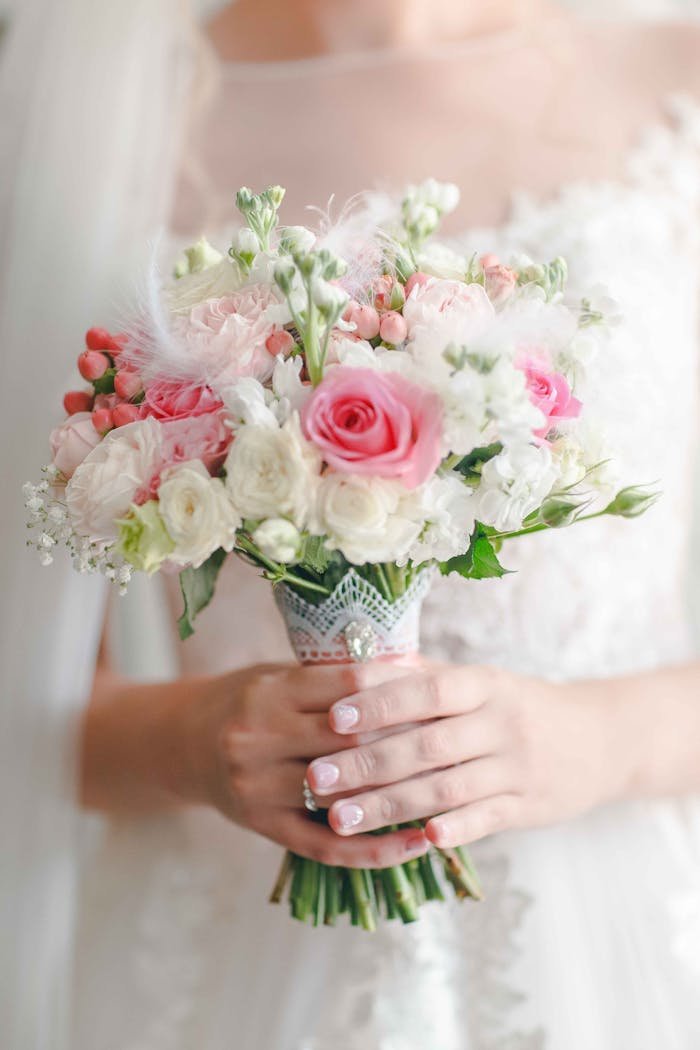 Soft pastel bouquet held by a bride, featuring roses and delicate florals for a romantic wedding vibe.