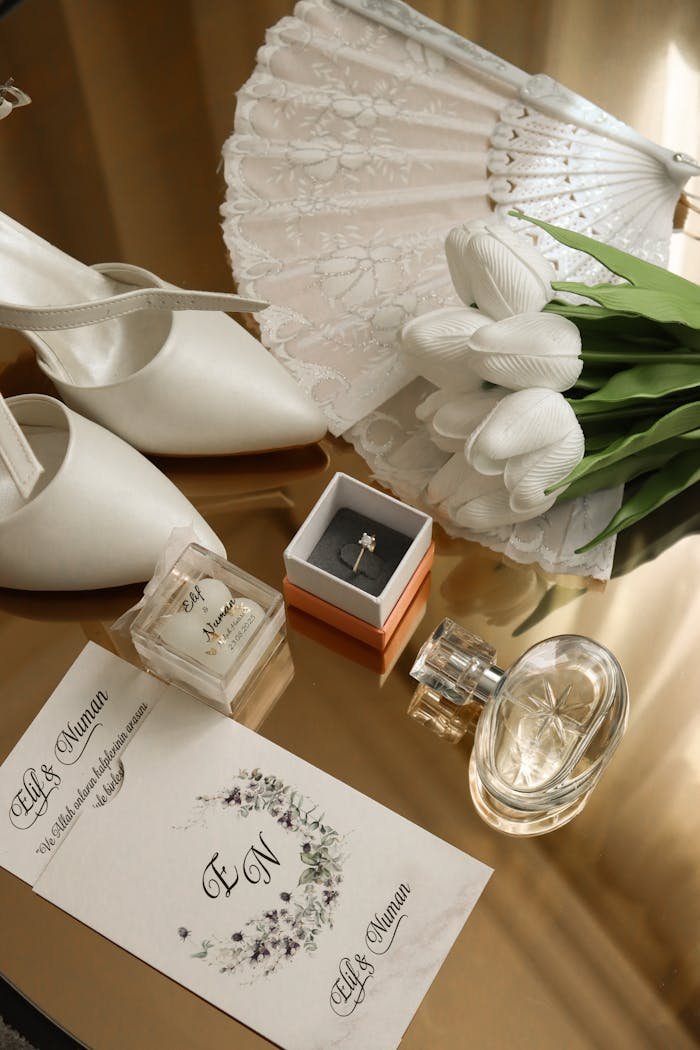 Flat lay of wedding accessories including shoes, fan, and bouquet on a gold surface.