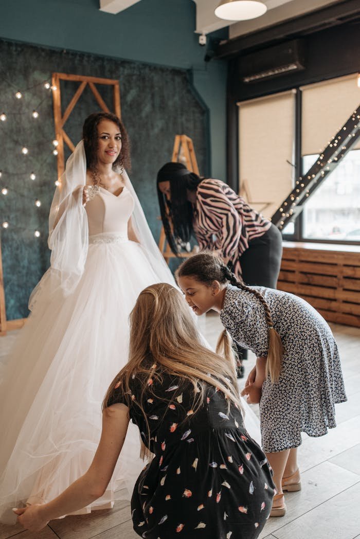 services-01 Bride in gown with assistants preparing for her wedding day indoors.